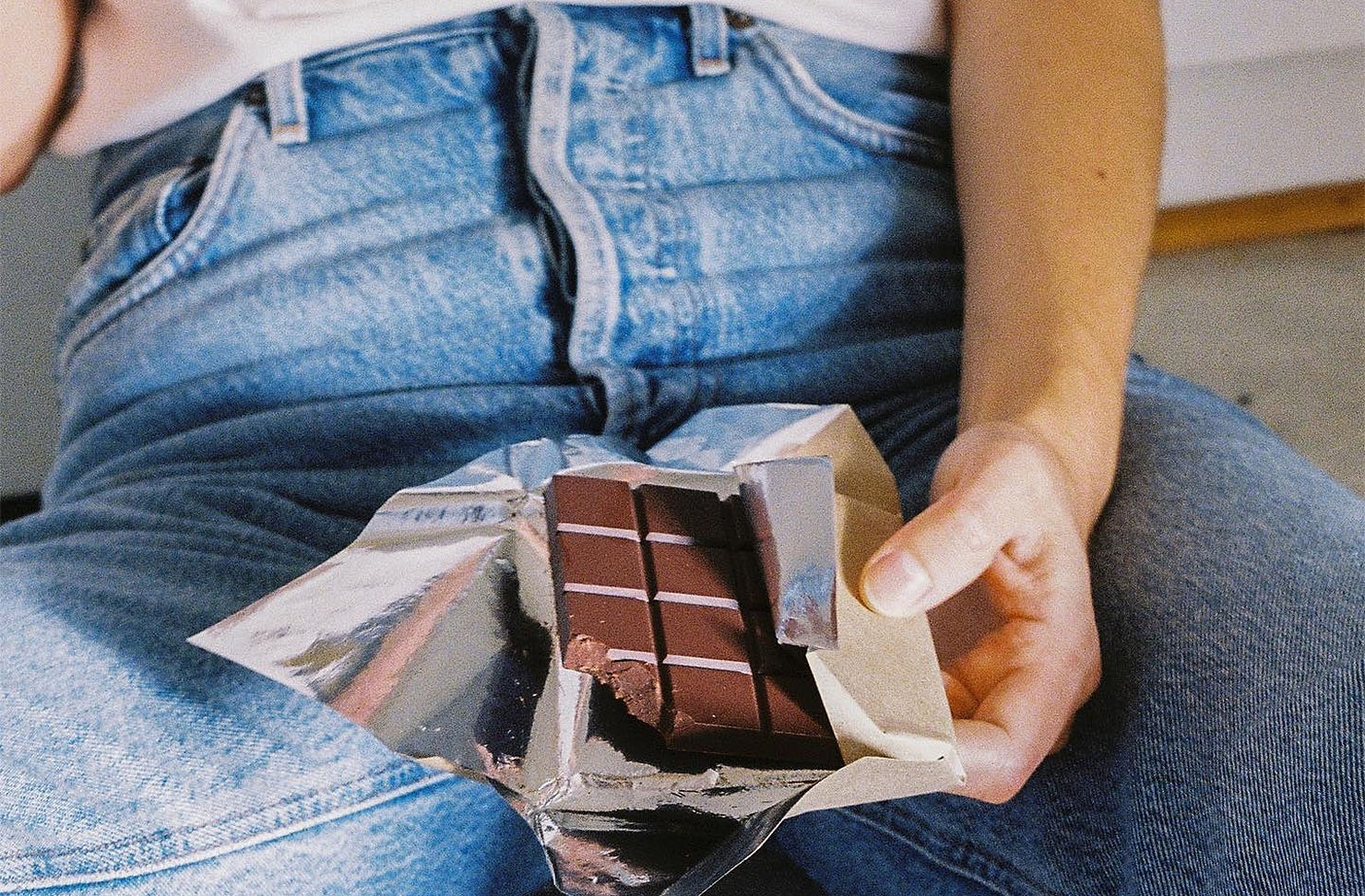 Someone sits with a bar of Flint Chocolate in their lap. One of the best craft chocolate makers in New Zealand.
