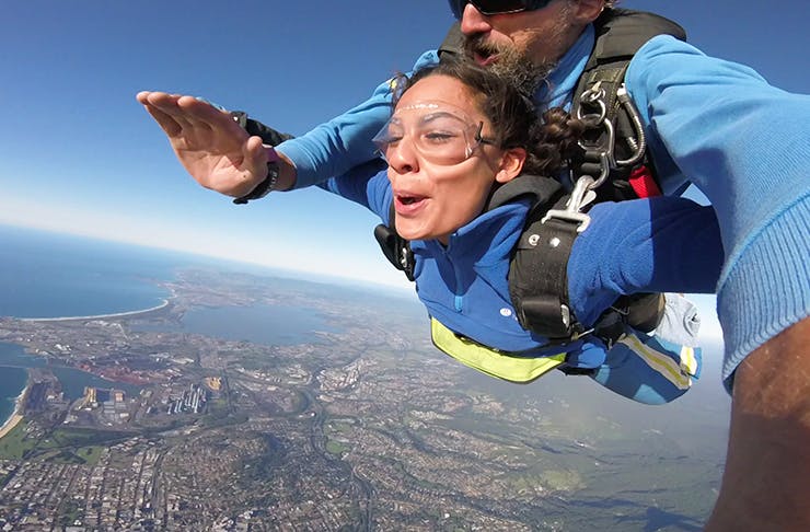 Women skydiving from plane with male instructor.