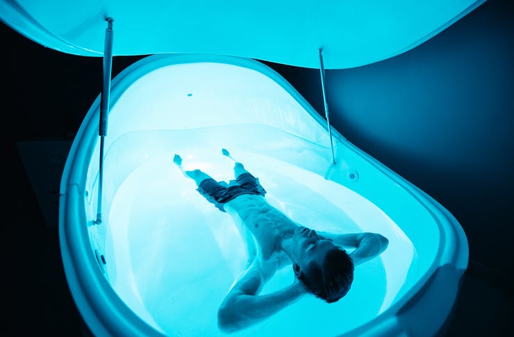 a man floating in a blue-lit pool