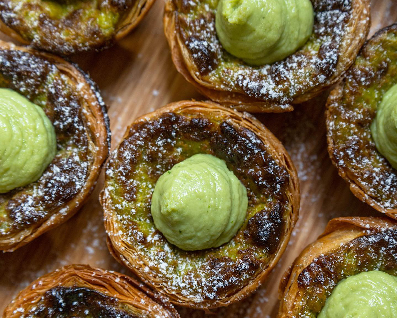 A mouthwatering lineup of pandan egg tarts from Fold’s Patisserie, one of the best places to eat at in Auckland this summer. 