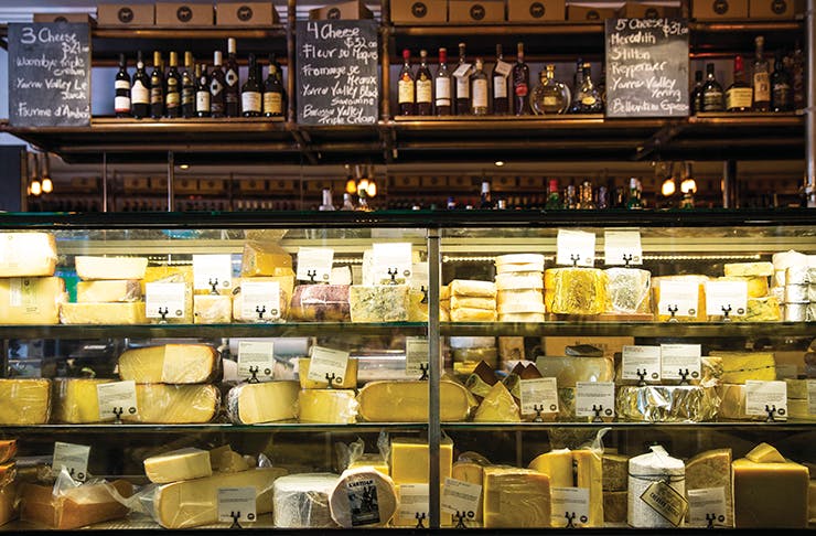 A cheese store with various cheeses on sale on a shelf.
