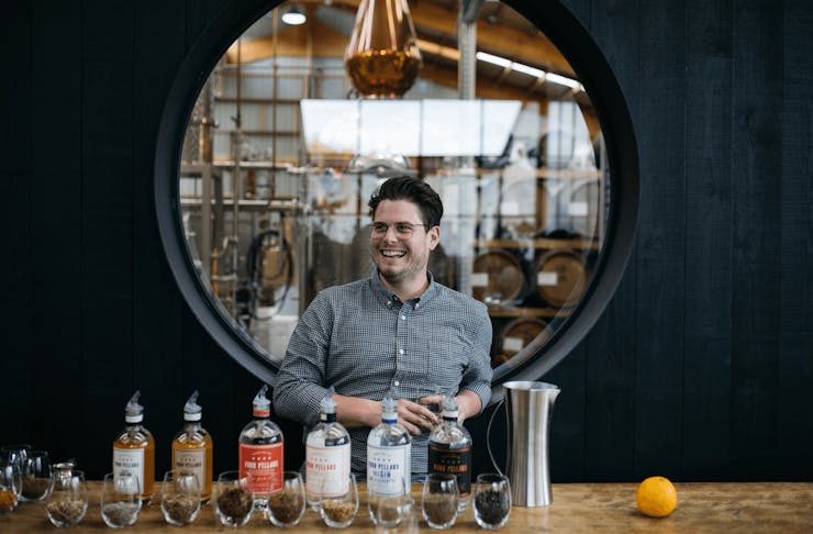 A person smiling with a selection of gin bottles in front of him. 
