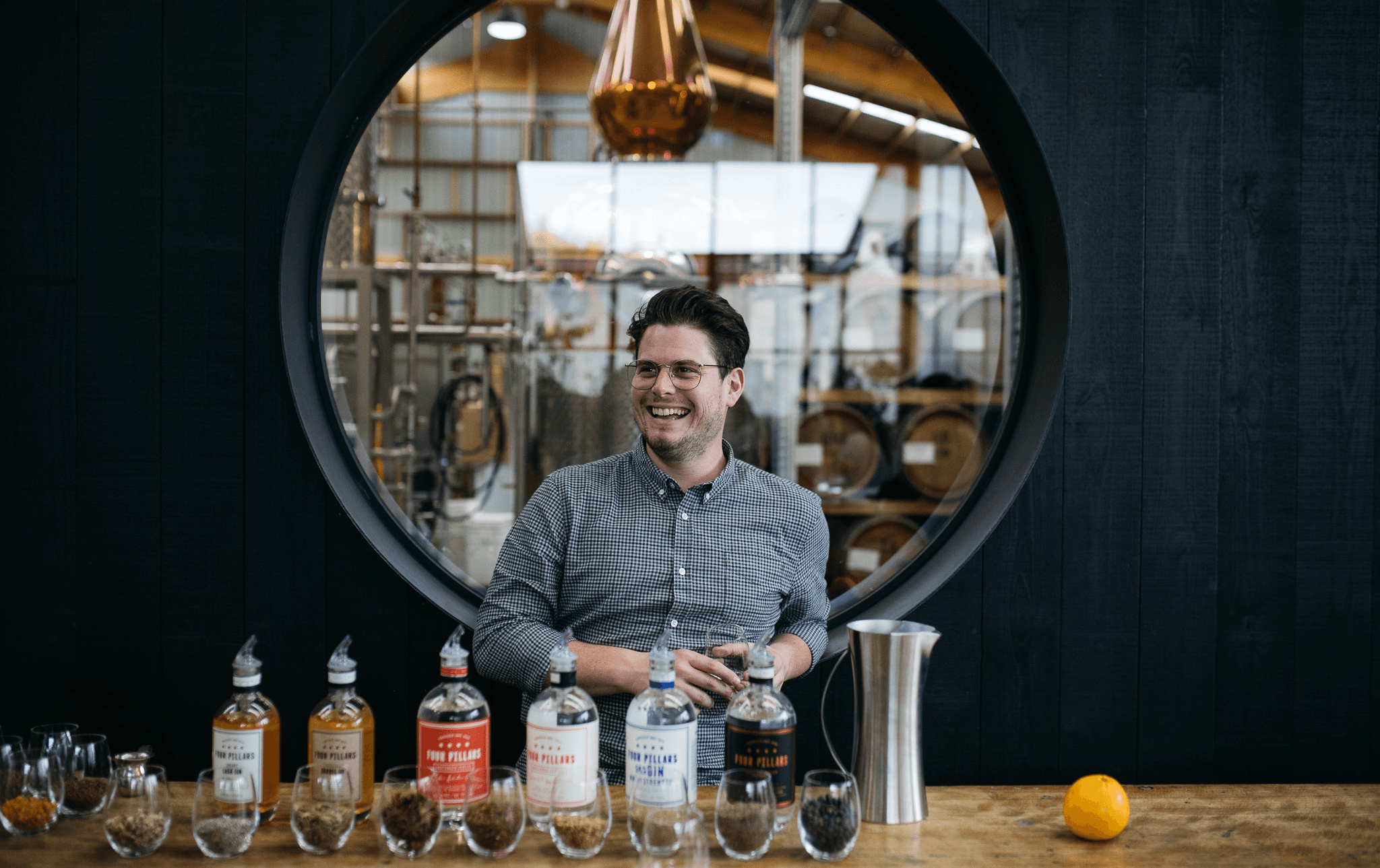 A person smiling with a selection of gin bottles in front of him. 