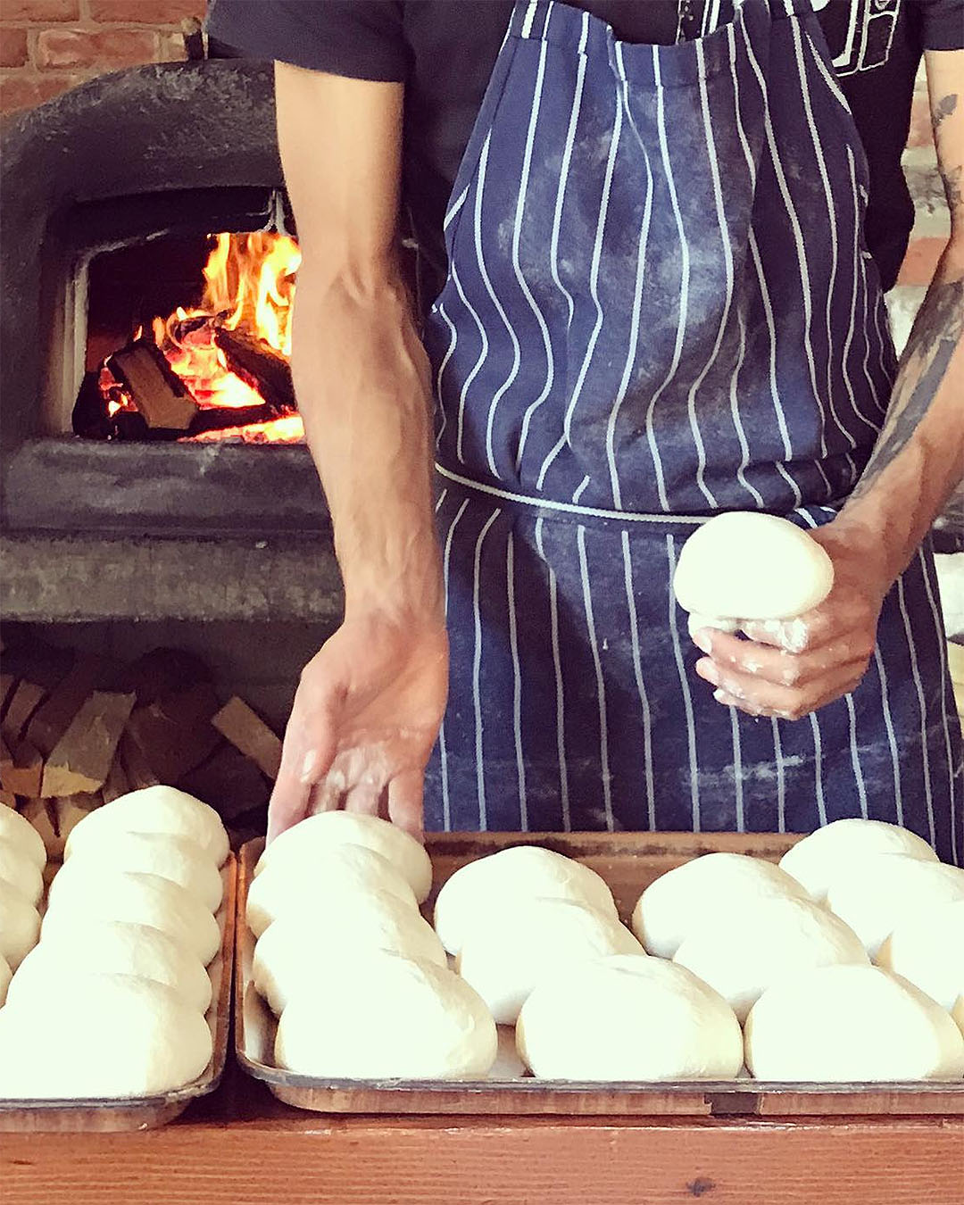 Someone stands in front of a pizza oven with balls of dough at Francesca's Italian Kitchen, one of the best restaurants in Wanaka.