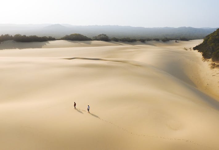 Two people trek across a vast and untouched sand blow on Fraser.