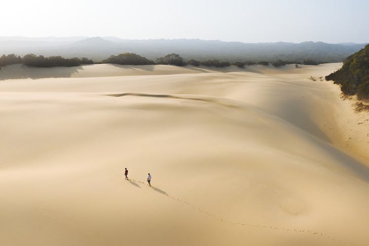 Two people trek across a vast and untouched sand blow on Fraser.