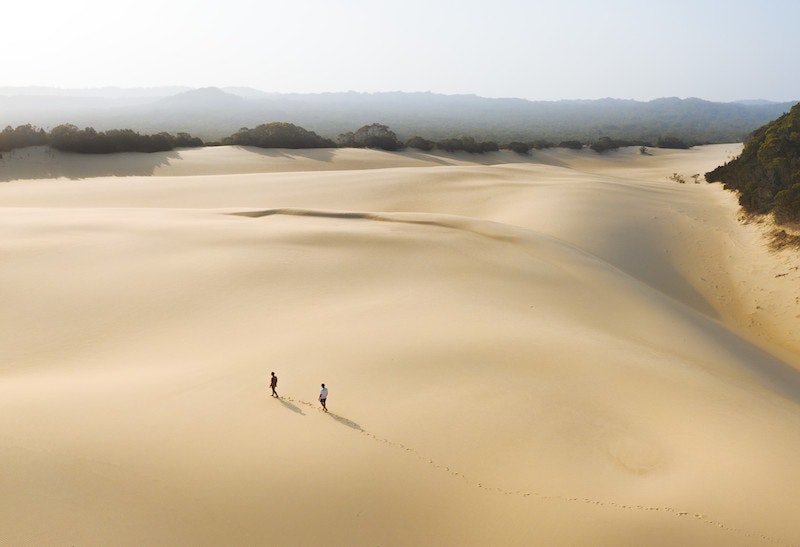 Two people trek across a vast and untouched sand blow on Fraser.