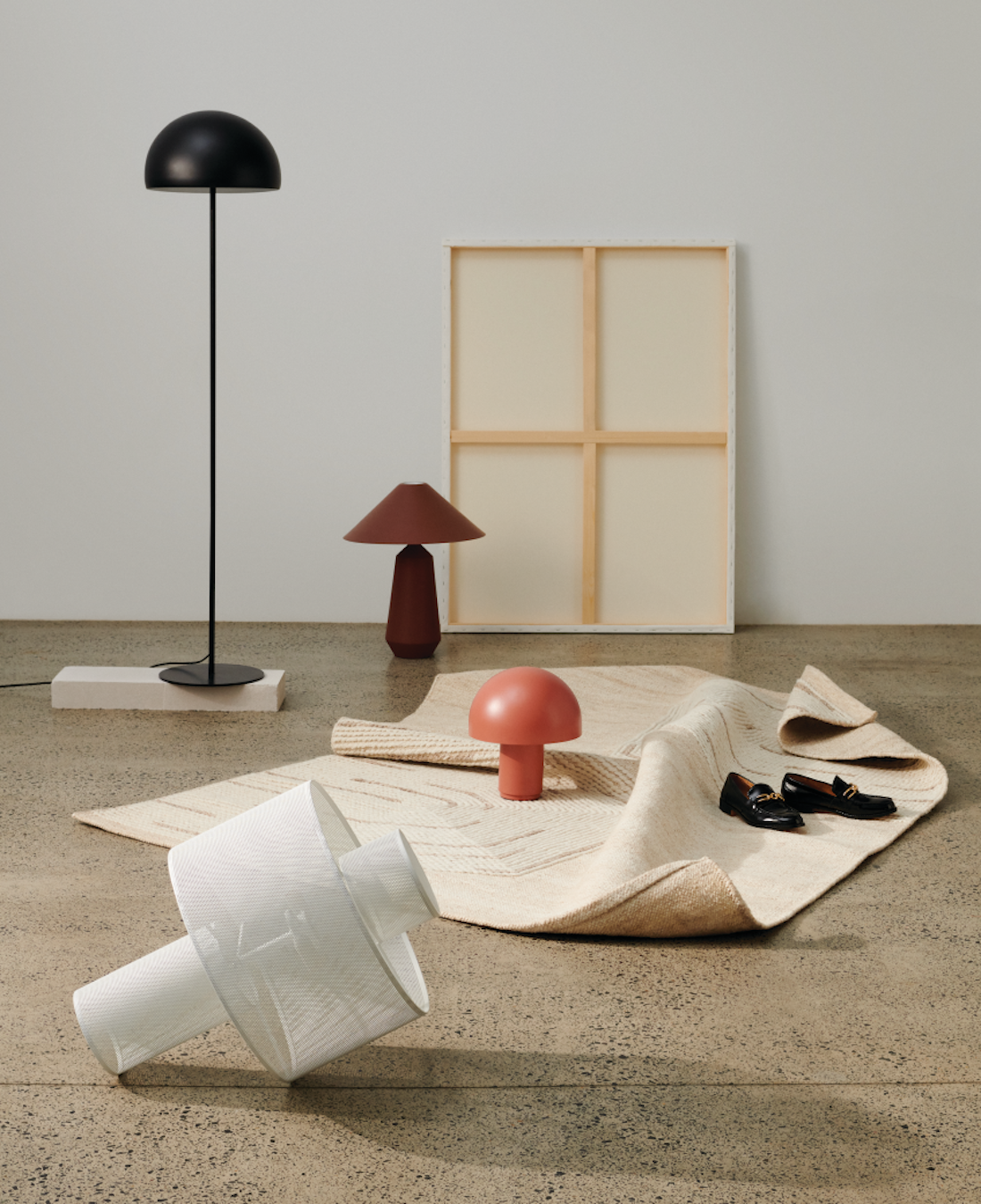 A range of short and tall mushroom lamps sit on a concrete floor.