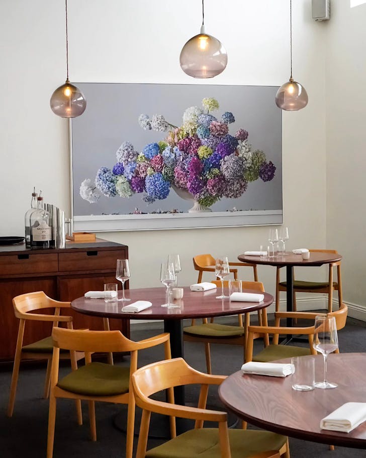 An airy, chic dining room with globe lights and a beautiful floral painting.