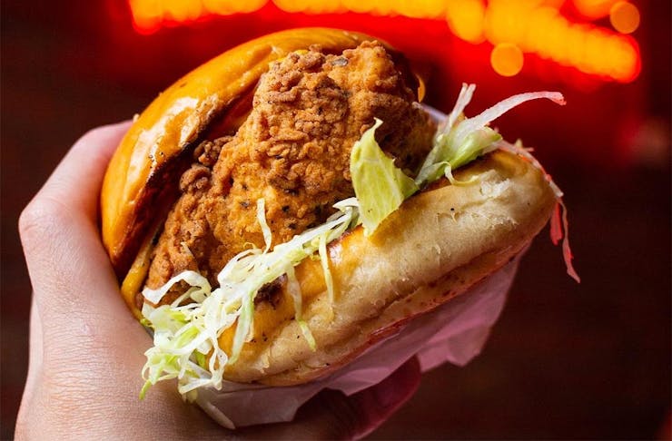 A hand grips a mighty looking chicken burger.