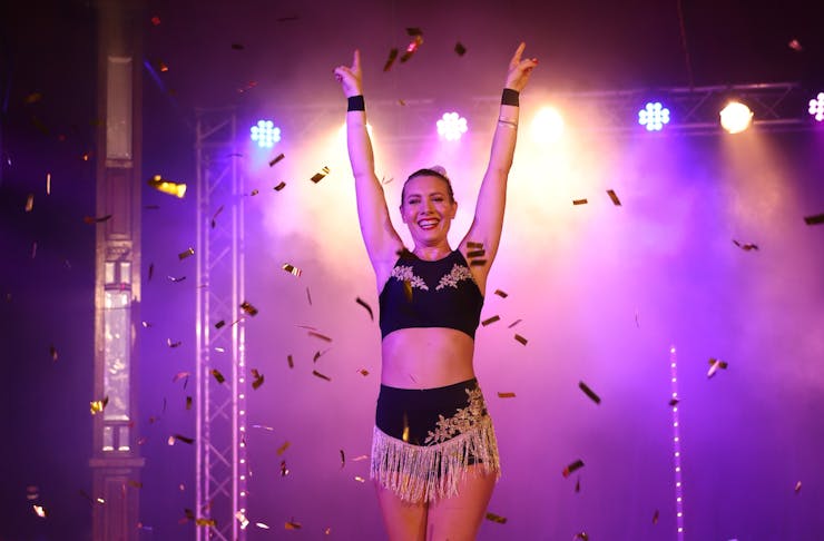 a performer on stage with her arms up as confetti falls