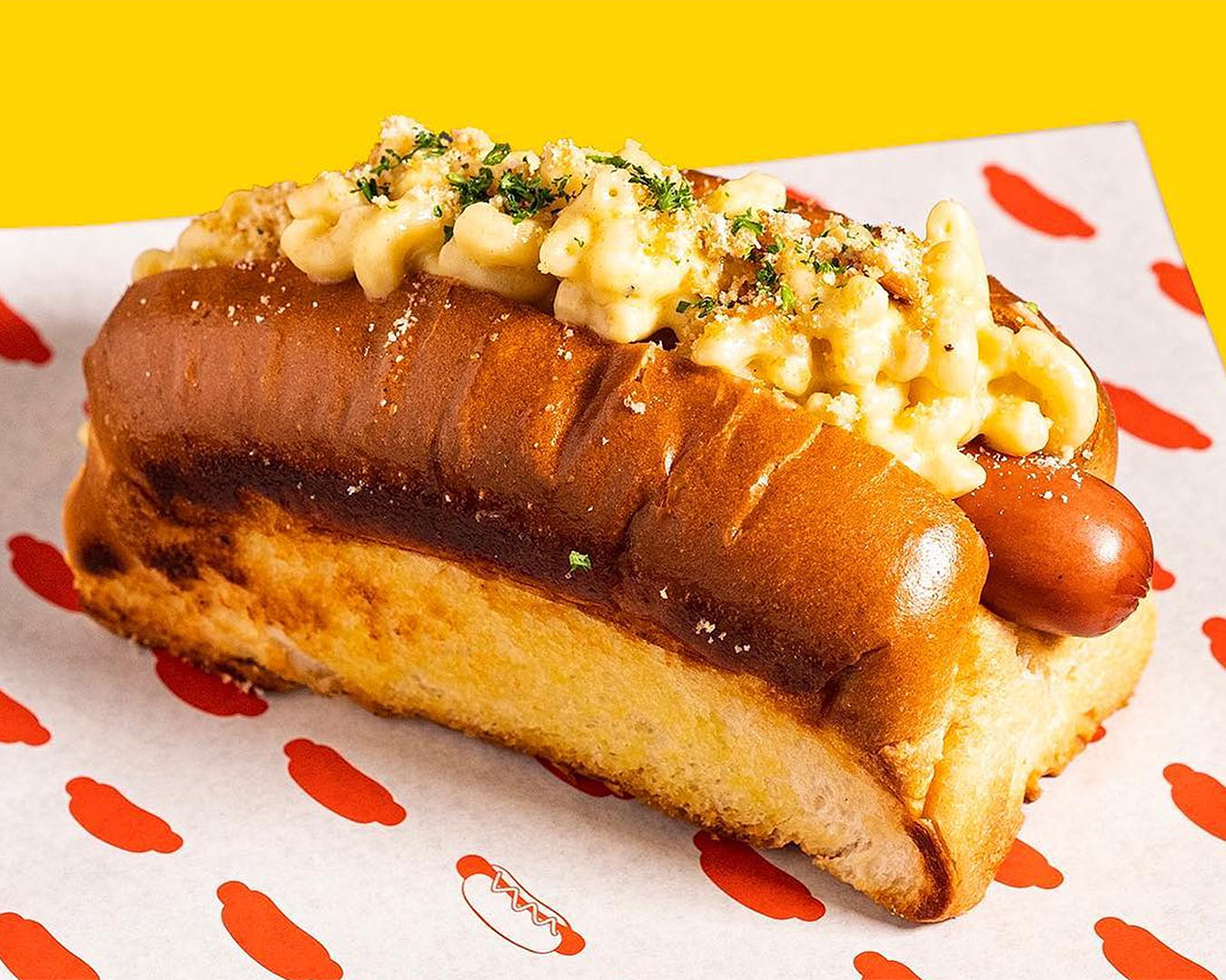 A mac 'n' cheese hot dog from GOOD DOG BAD DOG sits on a plate looking delicious.