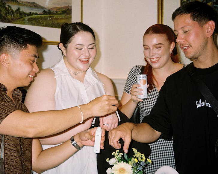 A group of people take turns using the GLOWGUARD pipette to apply sun protection.