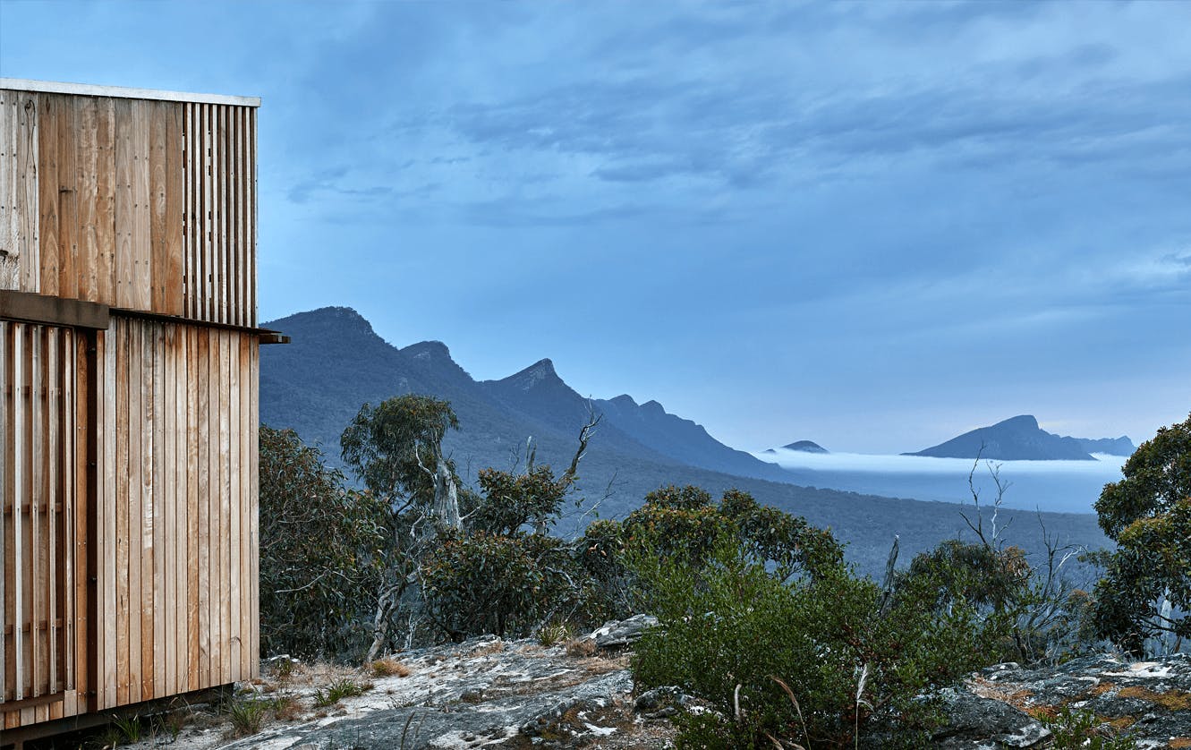 A cabin on a hill overlooking a wide mountain range.