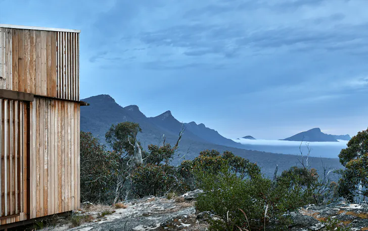 A cabin on a hill overlooking a wide mountain range.