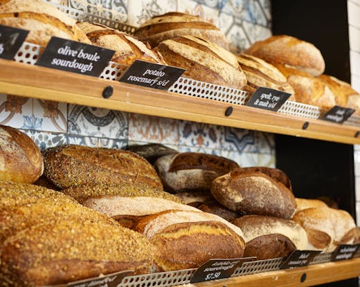 2 shelves of bread loaves on a wall. 