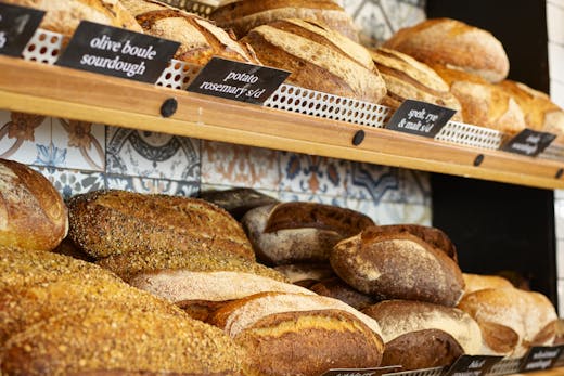 2 shelves of bread loaves on a wall.