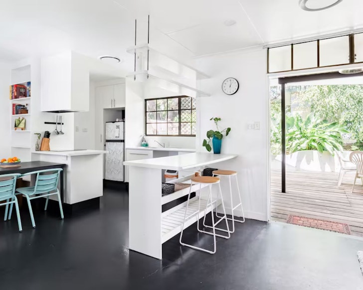 A view of the kitchen and dining space looking out to the garden deck at Gatehouse By The Gardens Airbnb one of the best Townsville stays