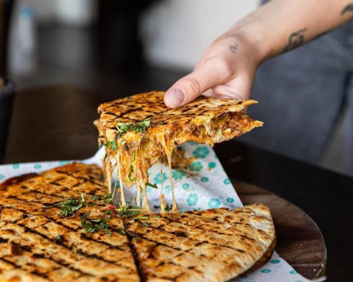Somebody picks up a slice of quesadilla and the mozzerella reluctantly acquiesces. 