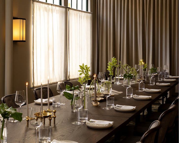 A long table adorned with greenery and candles at The Vault in Gilt Brasserie.