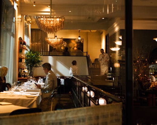 The inside of Gimlet Melbourne lit up at night with people dining. 