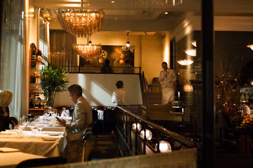 The inside of Gimlet Melbourne lit up at night with people dining.