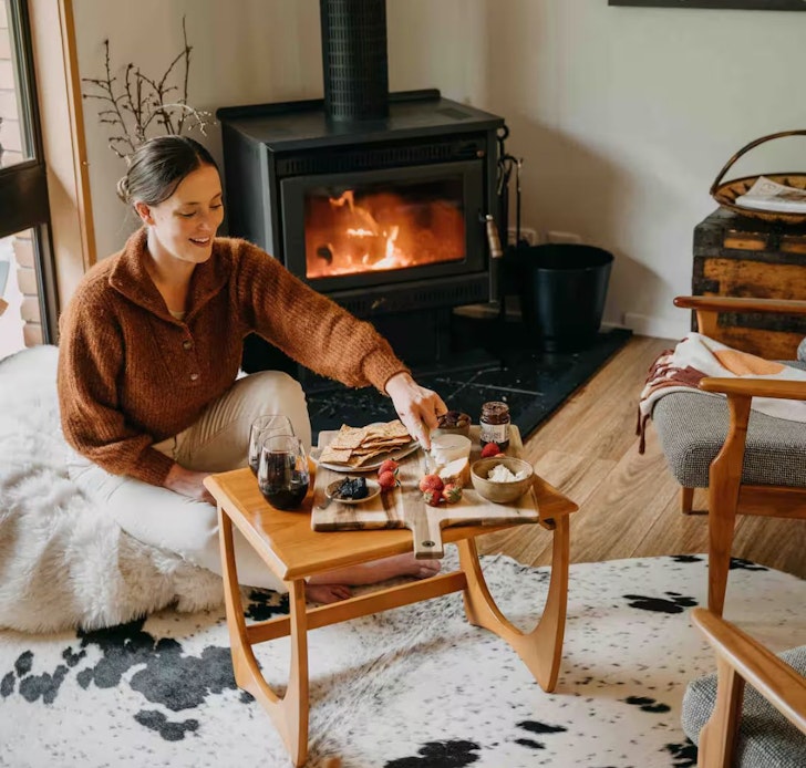 A woman in front of the roaring fireplace at Gingers on the Hill Airbnb Victoria
