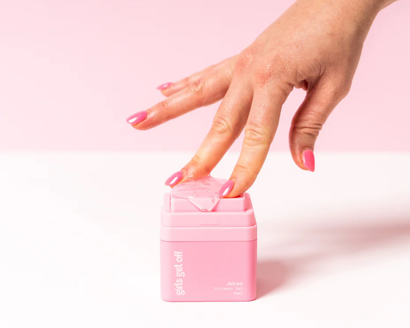 Somebody seductively spreads their fingers through some Juicee lube on the top of a pink container. 