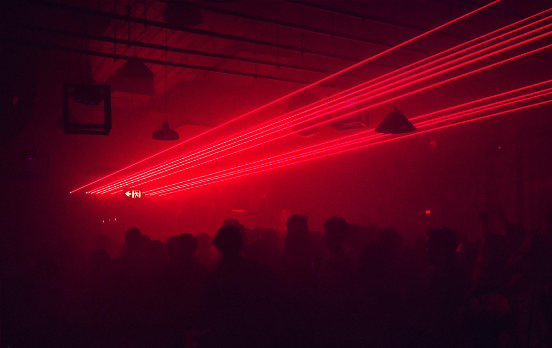 A smokey dance floor with beaming red neon lights inside the best nightclub in Melbourne.