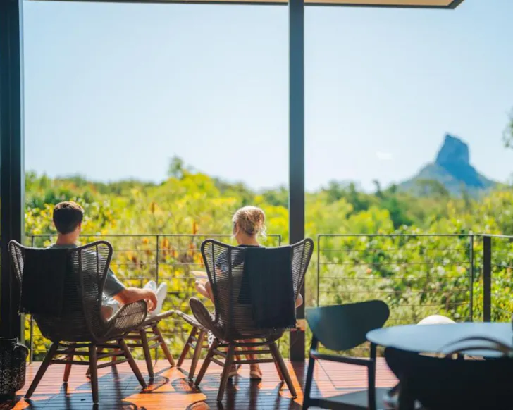 A couple enjoys a view of the Glasshouse Mountains from Glass On Glasshouse one of the best romantic getaways in Australia
