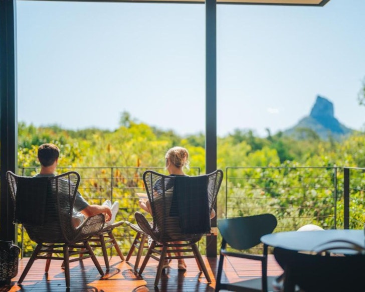 A couple enjoys a view of the Glasshouse Mountains from Glass On Glasshouse one of the best romantic getaways in Australia
