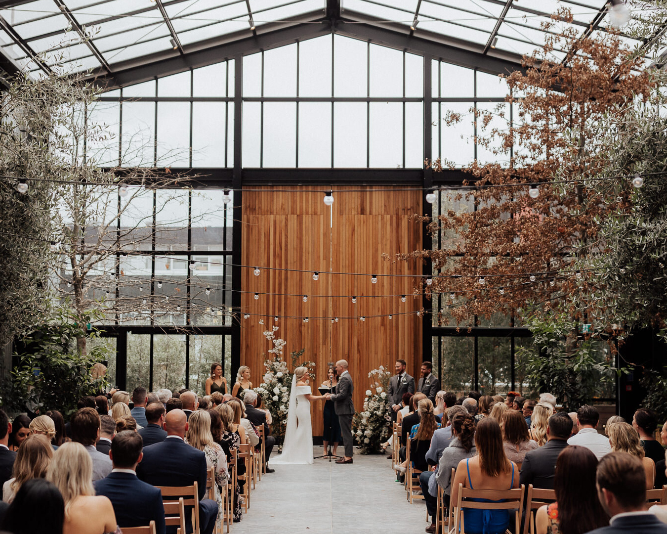 Wedding ceremony inside large glasshouse