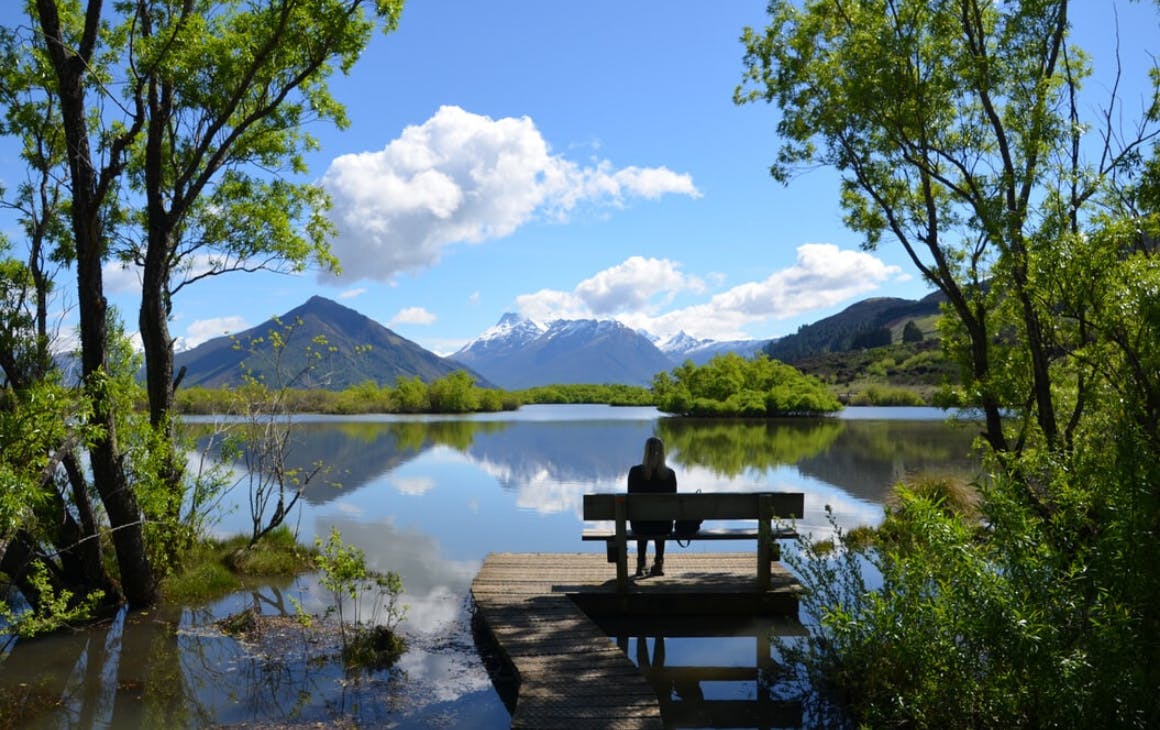Someone sits on a peaceful bench looking out over a beautiful vista in Glenorchy.