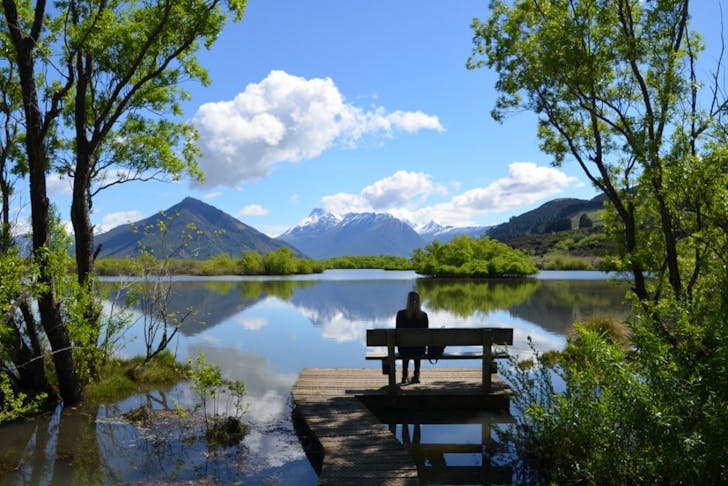 Someone sits on a peaceful bench looking out over a beautiful vista in Glenorchy.