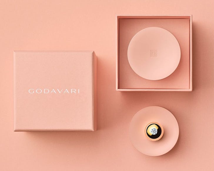 Godavari's Gold Globe with a diamond on the top, on a pink round platform next to boxes