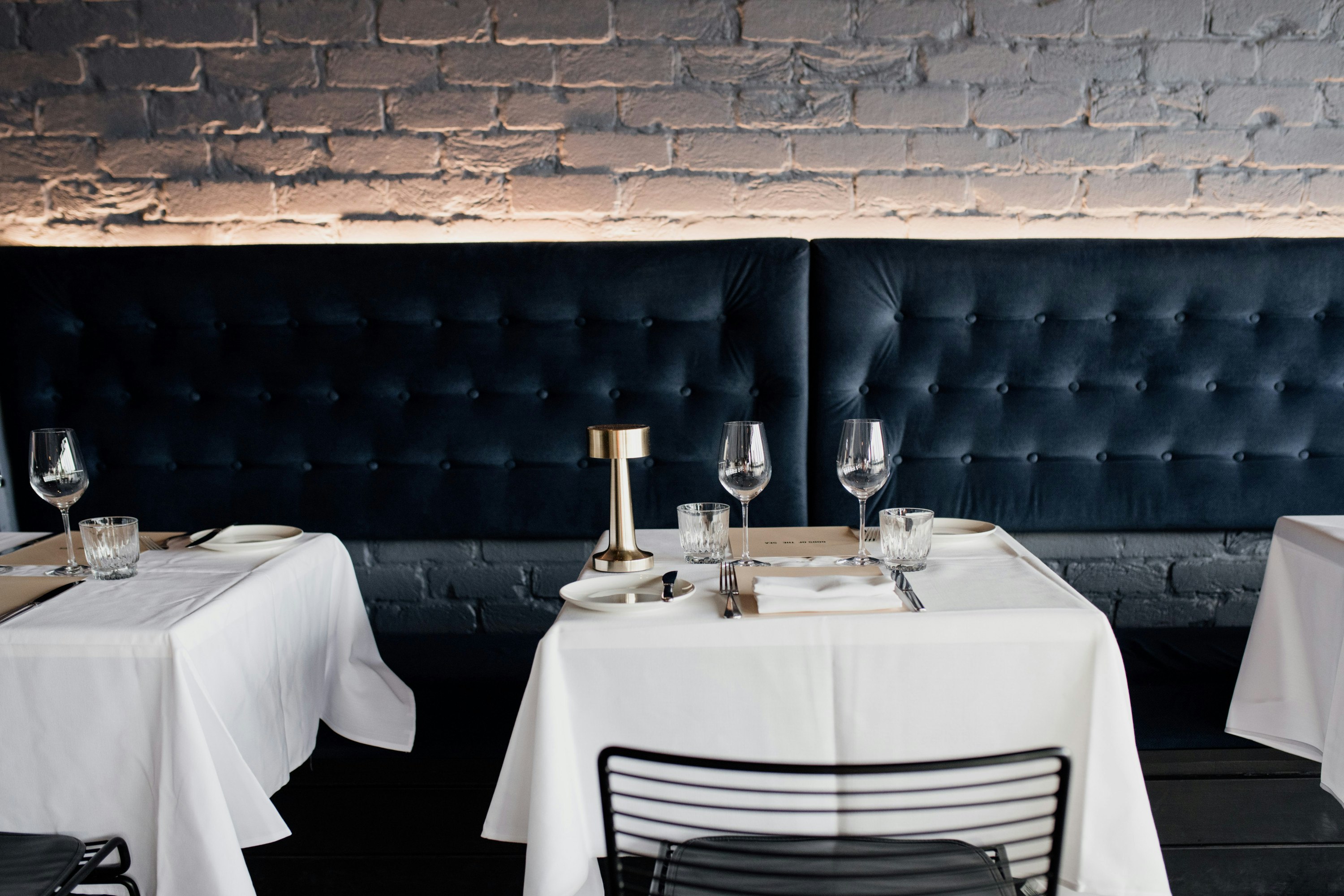 a navy blue bench and tables with white tablecloths 