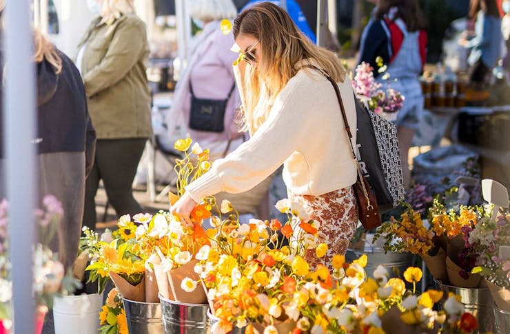 a woman browsing a market stall full of flowers