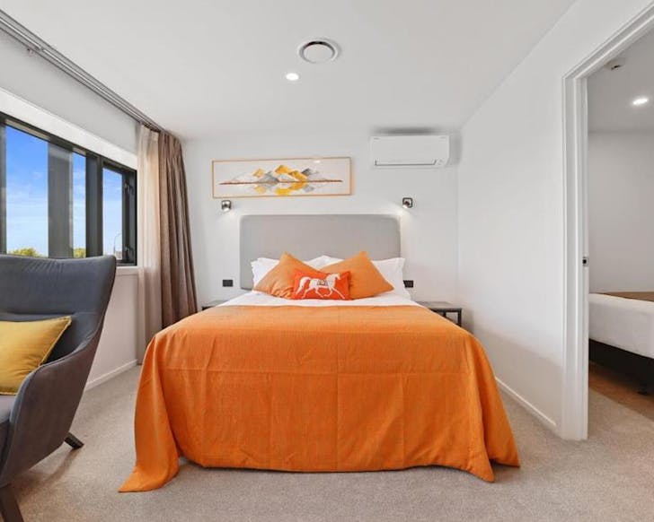 Cute white and orange bed in a clean hotel room. 