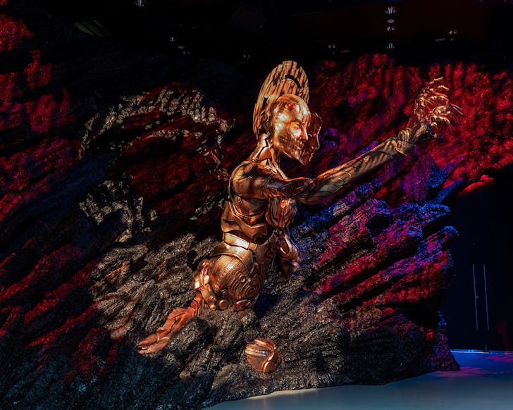A massive golden statue of a person emerges from rock at WÄtÄ Workshop Unleashed. 