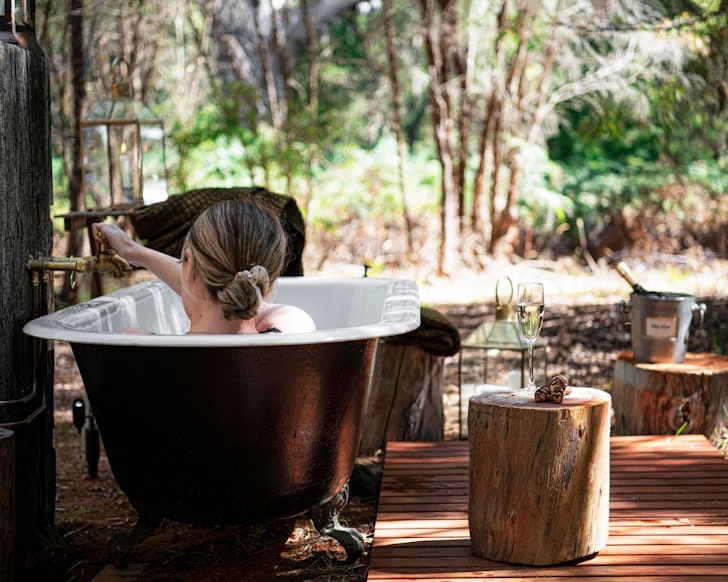 A woman relaxes in the outdoor bath at Gourmet Glamp best Airbnbs WA