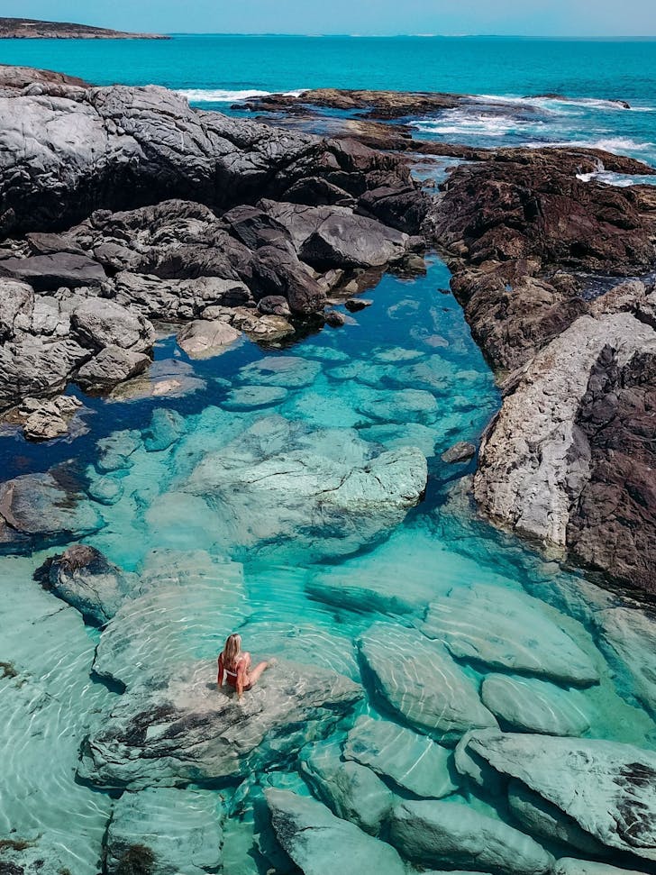 A person float in a rock pool by the beach