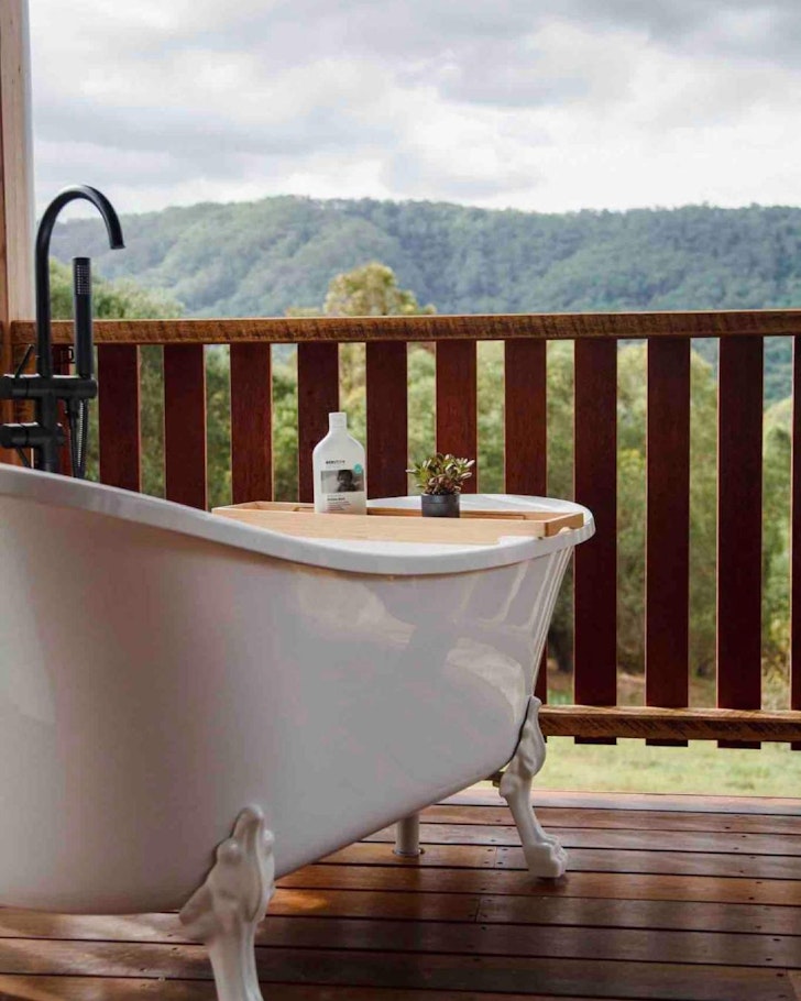 A view of the white clawfoot outdoor bath at Grey Gum Eco Luxury Cottage Airbnb near Brisbane, Queensland