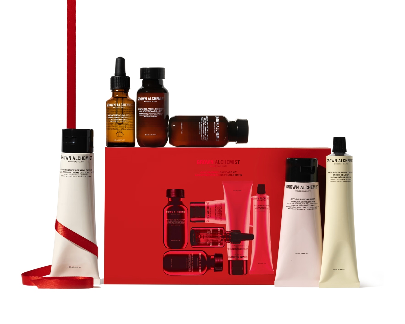 Six tubes and bottles of skincare styled around a red Grown Alchemist gift box.