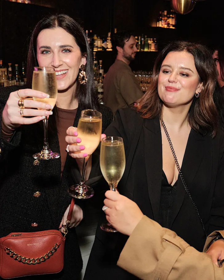 Three women toast with champagne at a rooftop party at HI-SO.