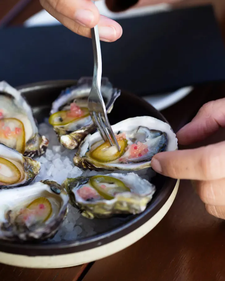 Plate of oysters with fork and hand