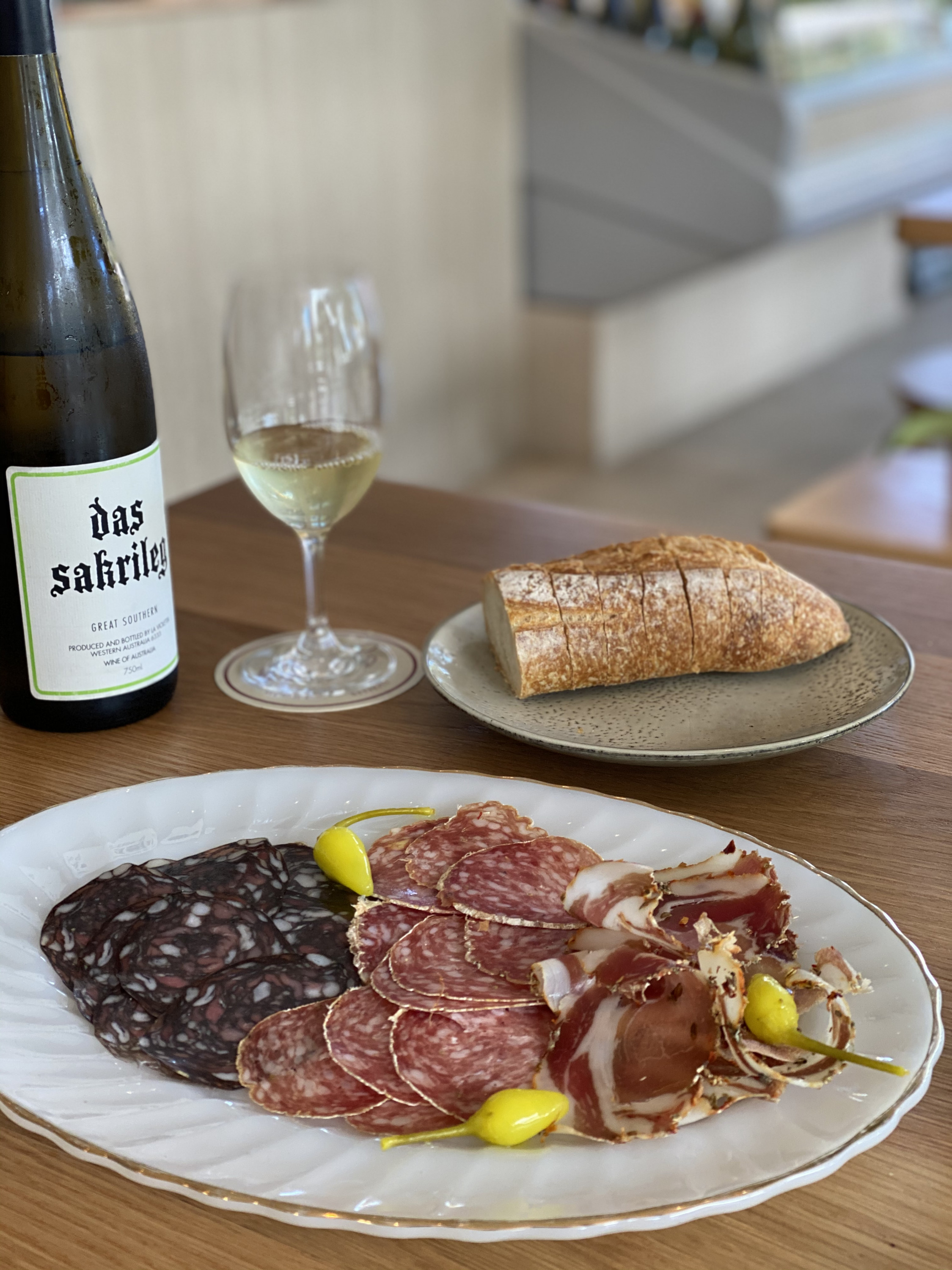 a generous salumi plate with a glass and a bottle of white wine in the background