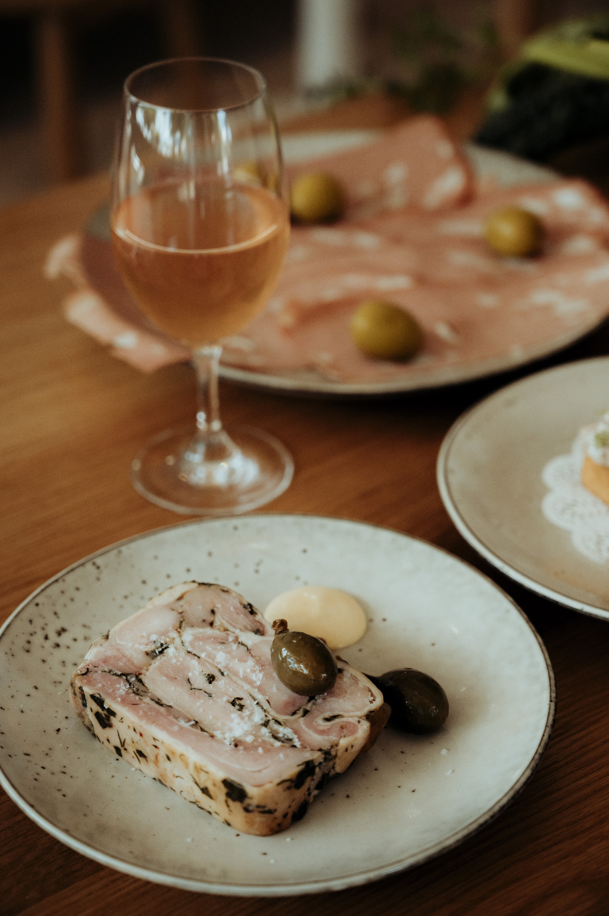 a glass of rose and scattered salumi plates