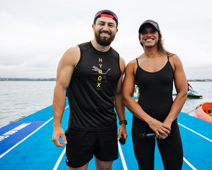 Hyrox ambassador Abbas Nazari and Micah Stiniato look happy on a blue floating pontoon.
