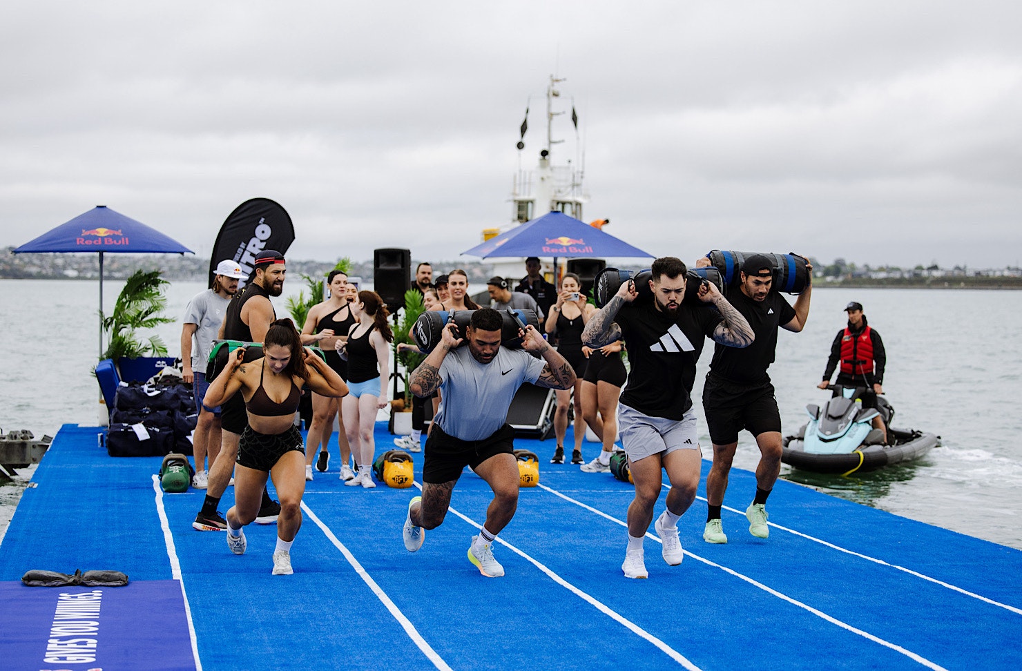Four fitness influencers tackle weighted lunges at a hyrox-inspired workout. 