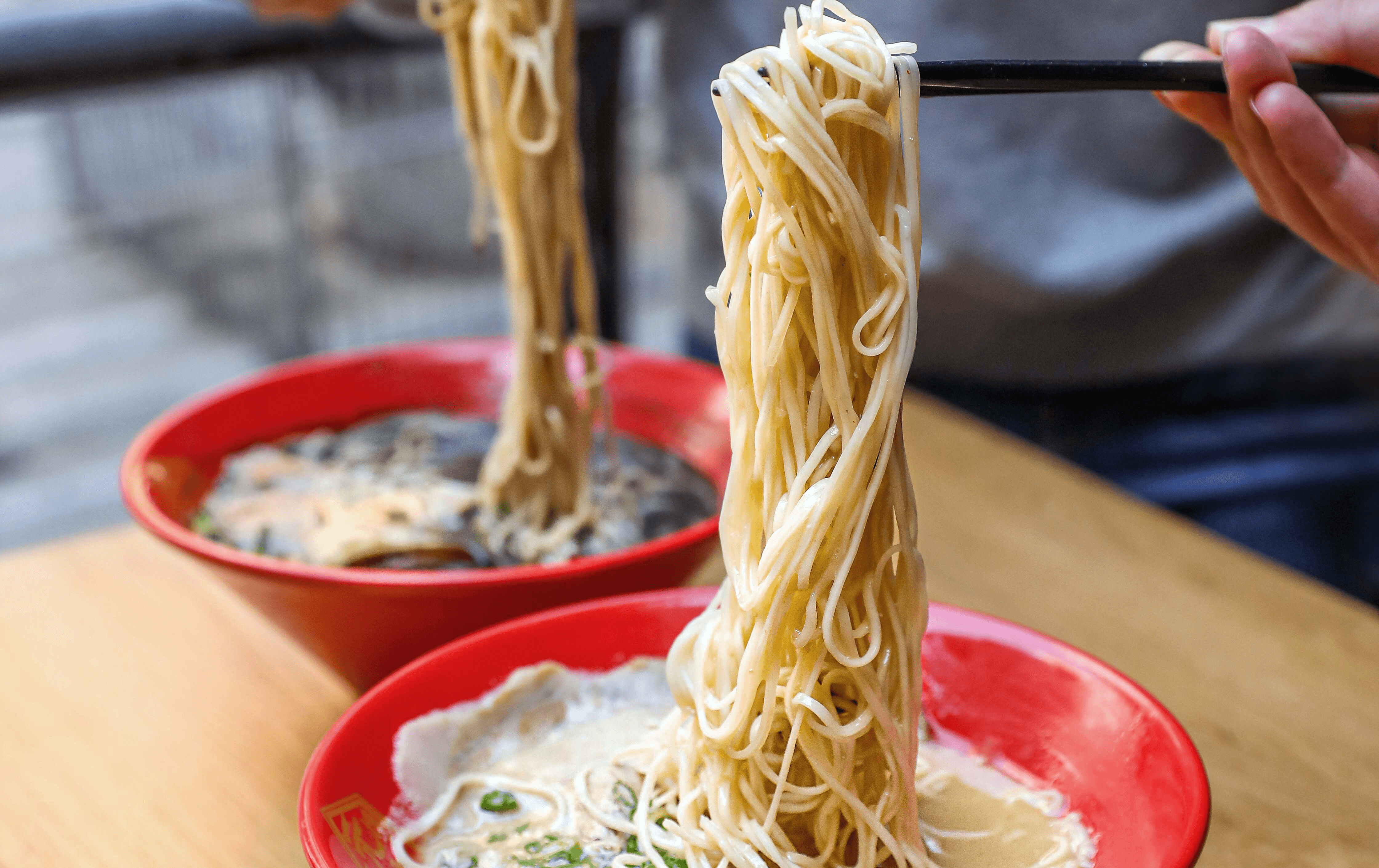 Two bowls of ramen with the noodles being lifted out at a best cheap eats Melbourne restaurant. 